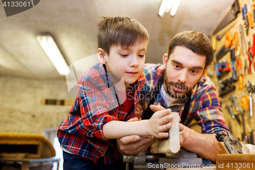 Image of father and little son with wood plank at workshop