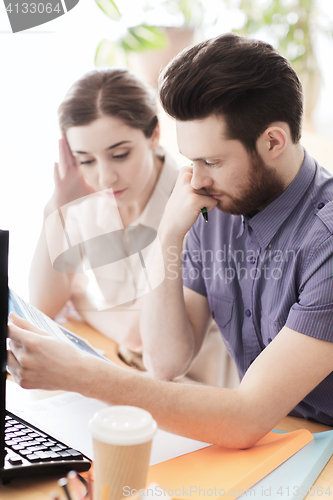 Image of creative team with reading paper in office