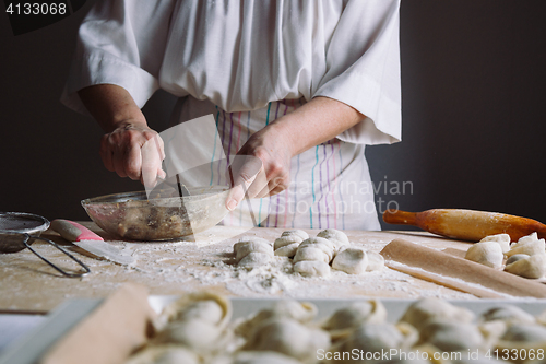 Image of Two hands making meat dumplings.