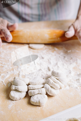 Image of Making meat dumpling with wooden rolling pin.