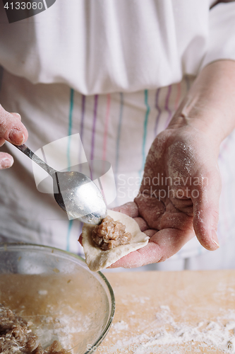 Image of Two hands making meat dumplings.
