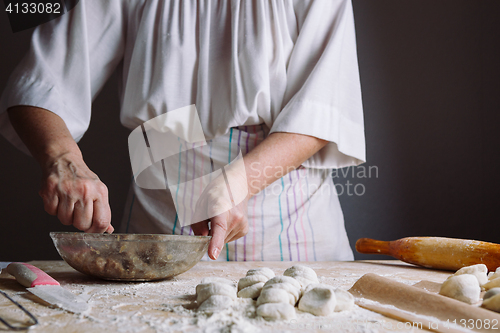 Image of Two hands making meat dumplings.