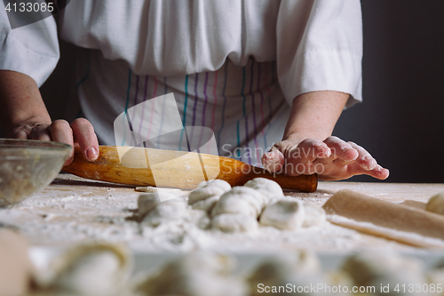 Image of Making meat dumpling with wooden rolling pin.