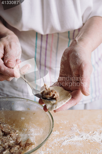 Image of Two hands making meat dumplings.