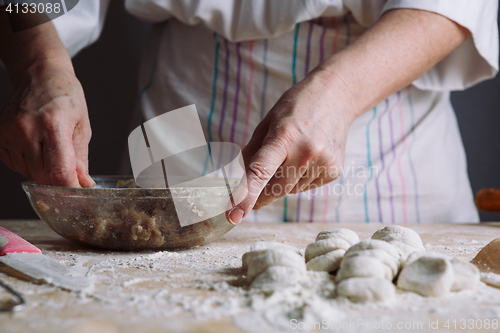 Image of Two hands making meat dumplings.