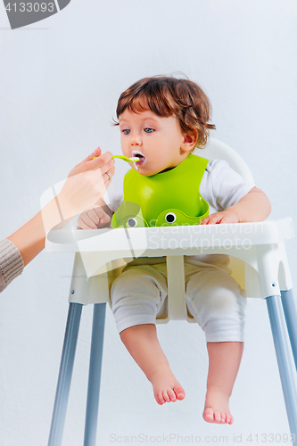 Image of Happy baby boy sitting and eating