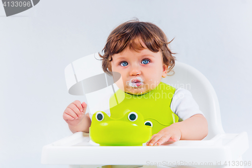 Image of Happy baby boy sitting and eating