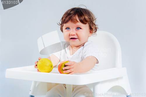 Image of Happy baby boy sitting and eating