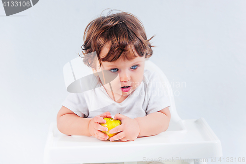 Image of Happy baby boy sitting and eating