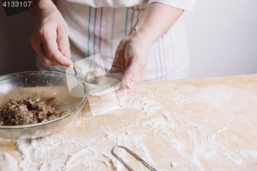 Image of Two hands making meat dumplings.