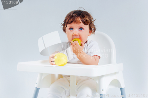 Image of Happy baby boy sitting and eating