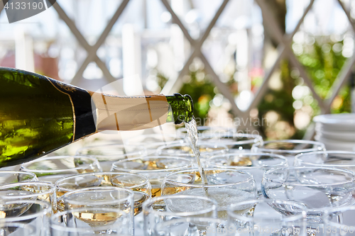 Image of Pouring champagne in flutes standing on table