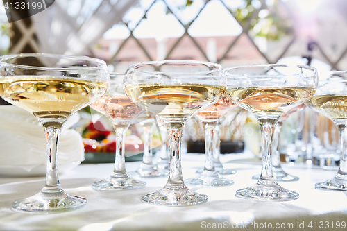 Image of Row of glasses filled with champagne are lined up ready to be served.