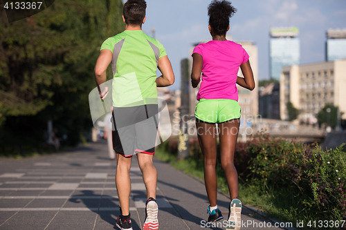 Image of young smiling multiethnic couple jogging in the city