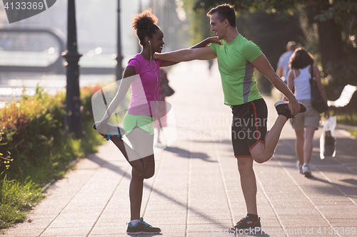 Image of jogging couple warming up and stretching in the city