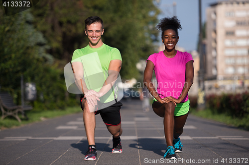 Image of jogging couple warming up and stretching in the city