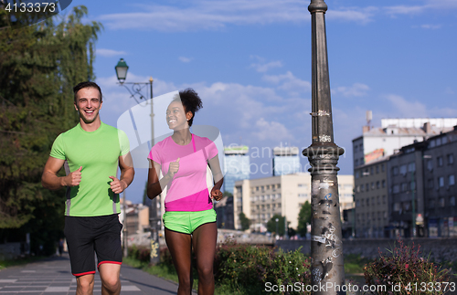 Image of young smiling multiethnic couple jogging in the city