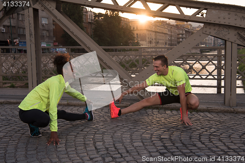 Image of jogging couple warming up and stretching in the city