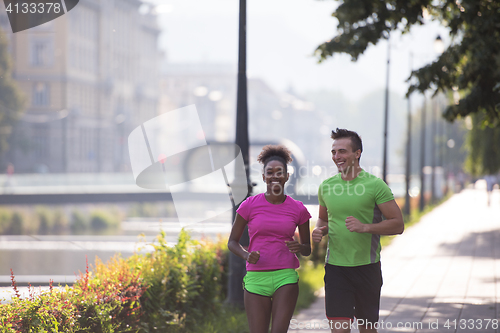 Image of young multiethnic couple jogging in the city