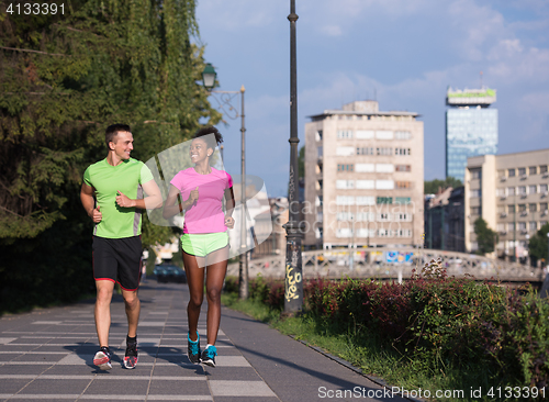 Image of young smiling multiethnic couple jogging in the city