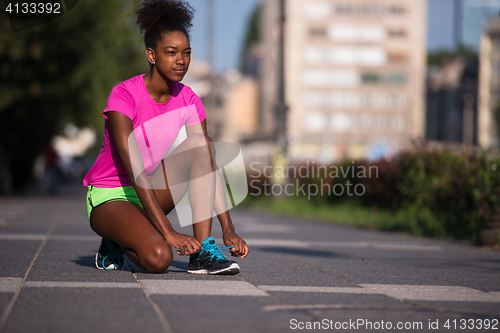 Image of African american woman runner tightening shoe lace