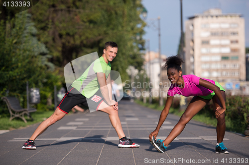 Image of jogging couple warming up and stretching in the city