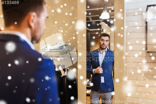 Image of man trying jacket on at mirror in clothing store