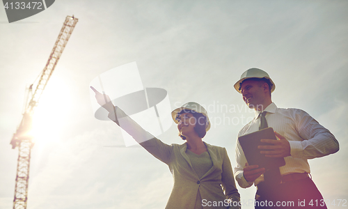 Image of happy builders in hardhats with tablet pc outdoors