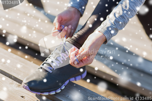 Image of close up of sporty woman tying shoelaces outdoors