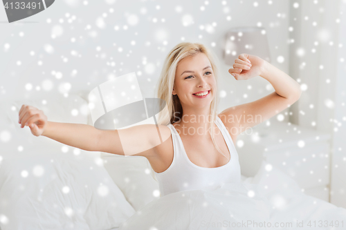 Image of young woman stretching in bed after waking up