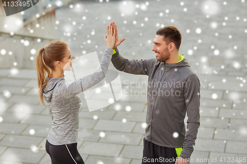 Image of happy couple giving high five outdoors