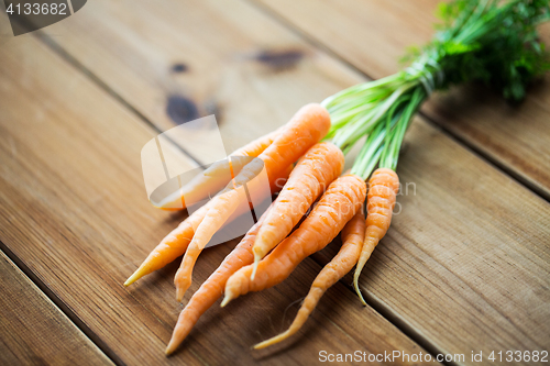 Image of close up of carrot bunch on wooden table