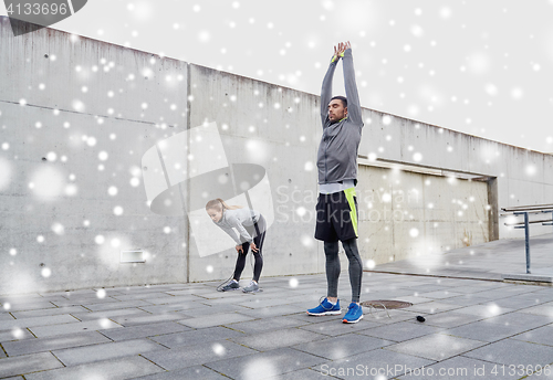 Image of couple with jumping ropes stretching outdoors