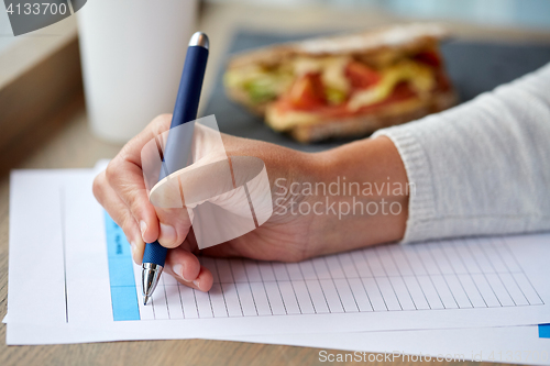 Image of woman with paper form having lunch at cafe