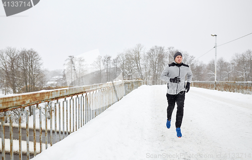 Image of man running along snow covered winter bridge road