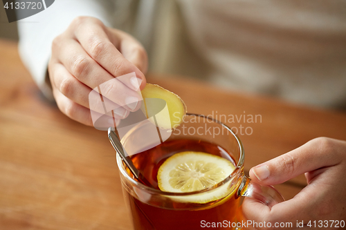 Image of close up of woman adding ginger to tea with lemon