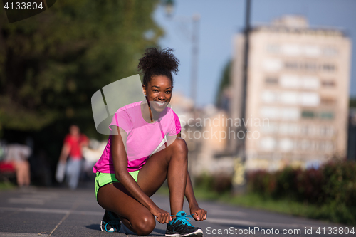 Image of African american woman runner tightening shoe lace