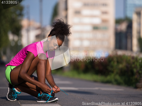 Image of African american woman runner tightening shoe lace