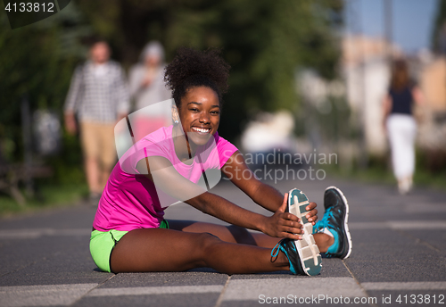 Image of sporty young african american woman stretching outdoors