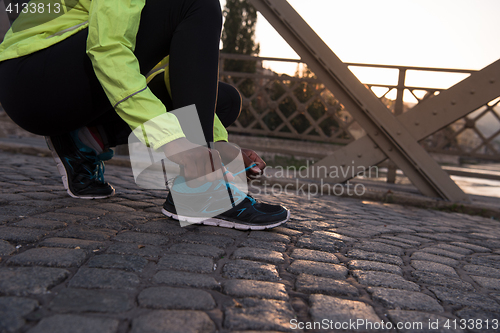 Image of African american woman runner tightening shoe lace