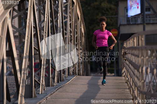 Image of african american woman running across the bridge