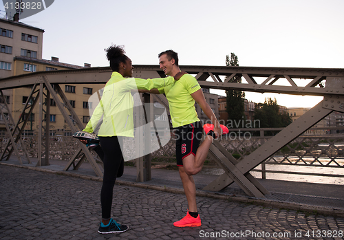 Image of jogging couple warming up and stretching in the city