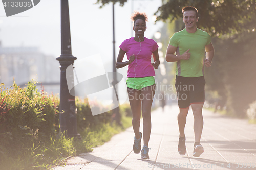 Image of young multiethnic couple jogging in the city