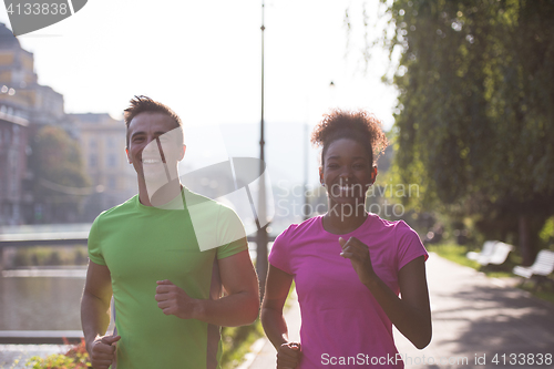 Image of young multiethnic couple jogging in the city