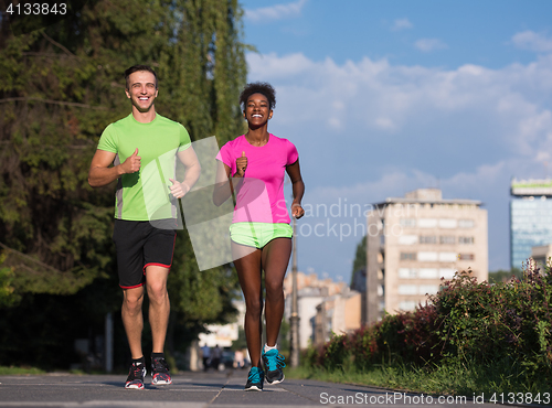 Image of young smiling multiethnic couple jogging in the city