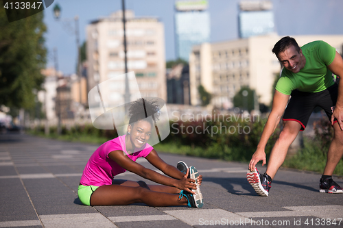 Image of jogging couple warming up and stretching in the city