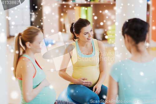 Image of happy pregnant women sitting on balls in gym