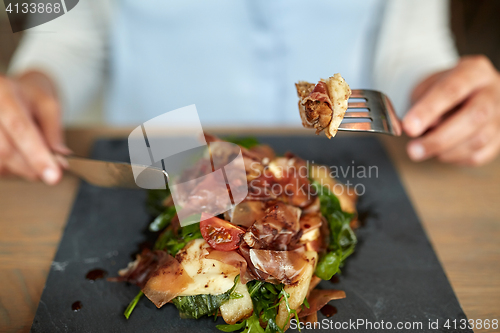 Image of woman eating prosciutto ham salad at restaurant