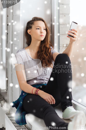 Image of sad pretty teenage girl with smartphone texting