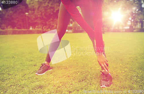 Image of close up of woman stretching leg outdoors